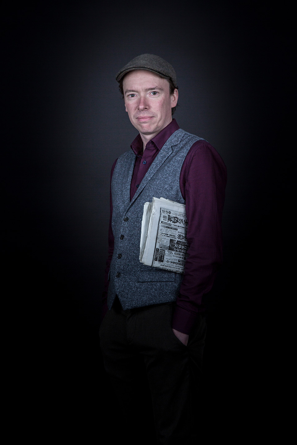 Portrait von Dennis Levin mit Zeitung unterm Arm